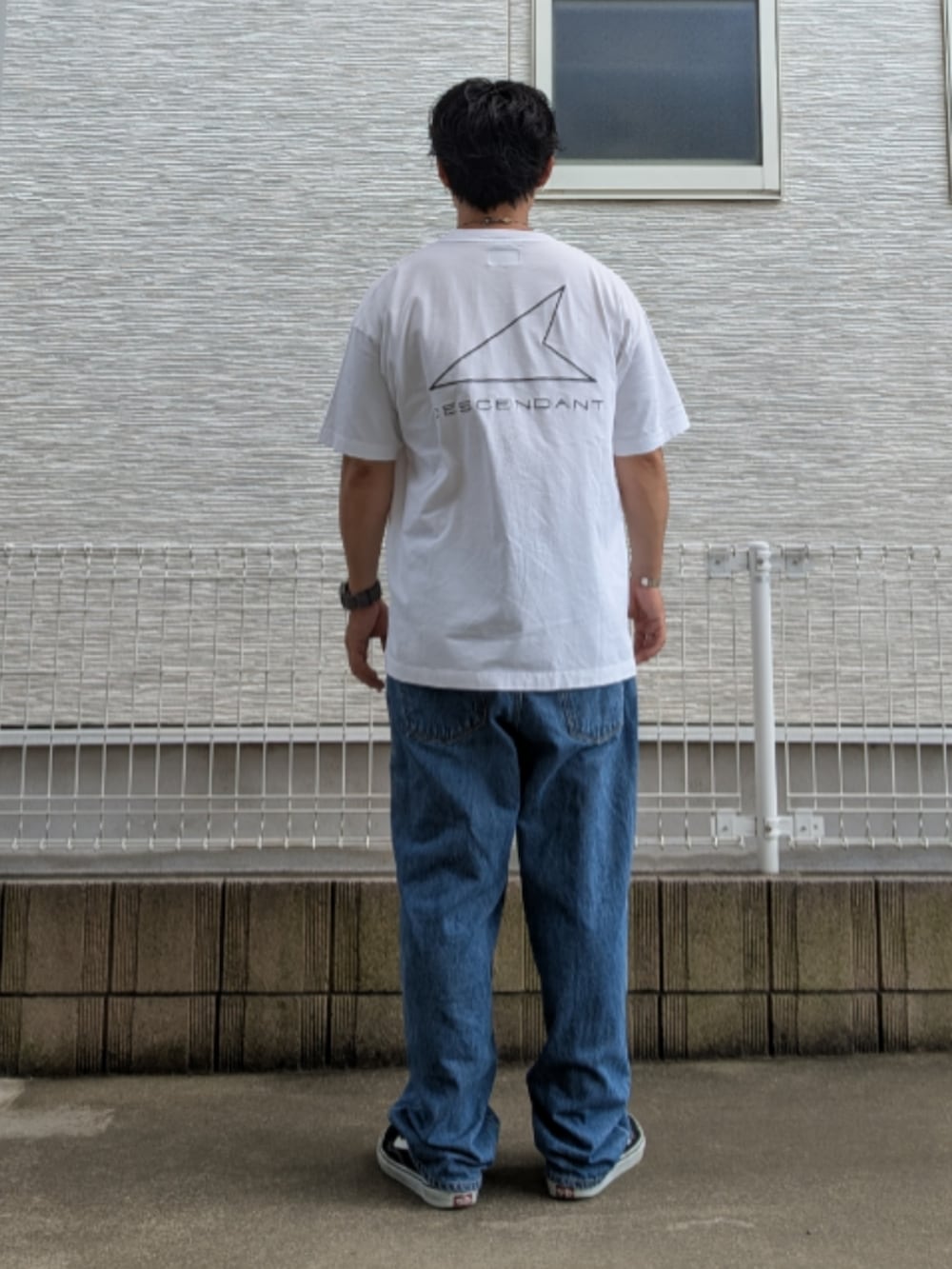 ブルー系のデニムパンツ、ブラック系のスニーカー、ホワイト系のTシャツ/カットソーを着用したメンズの夏コーディネートの2枚目の写真