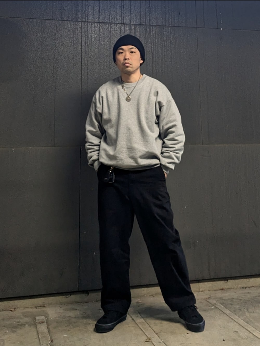 グレー系のスウェット、ブラック系のチノパンツ、ブラック系のスニーカーを着用したメンズの冬コーディネートの2枚目の写真