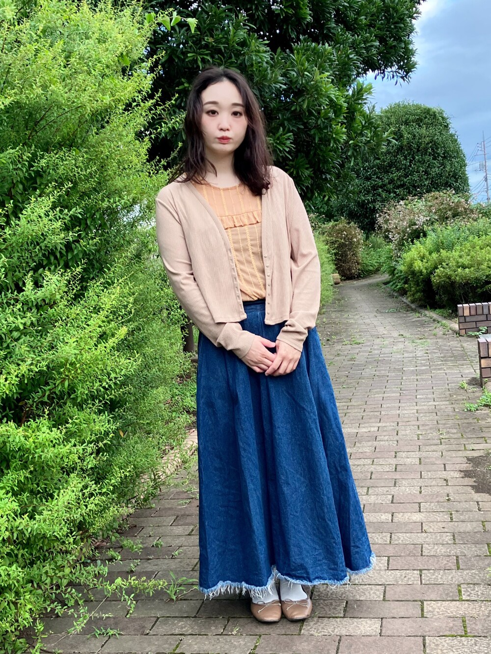 ベージュ系のカーディガン/ボレロ、ブラウン系のシャツ/ブラウス、ブルー系のデニムスカートを着用したレディースの秋コーディネートの2枚目の写真