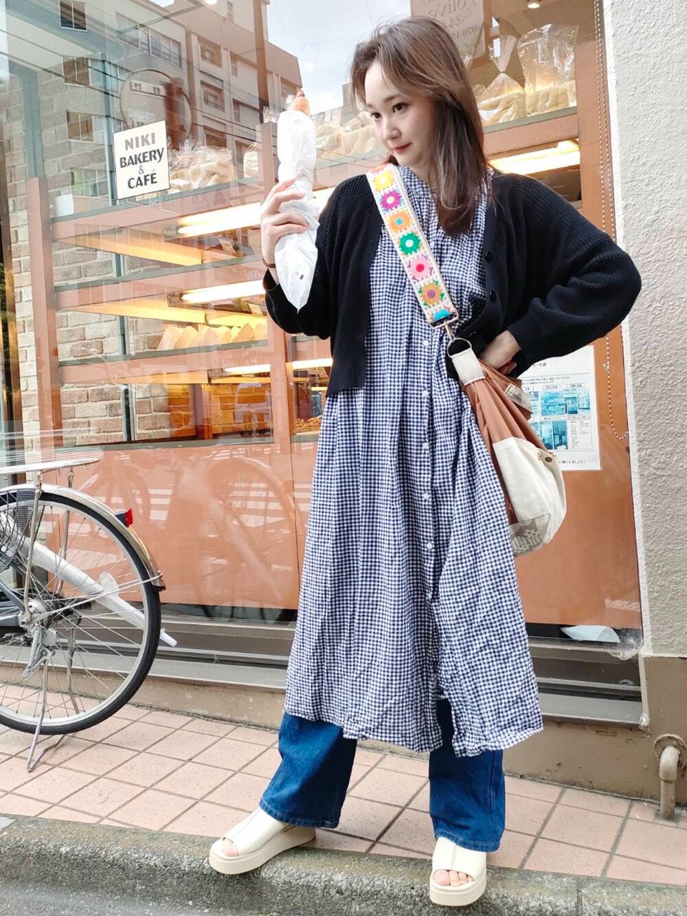 ブラウン系のショルダーバッグ、ブラック系のワンピース/ドレス、ブルー系のデニムパンツを着用したレディースの春コーディネートの2枚目の写真