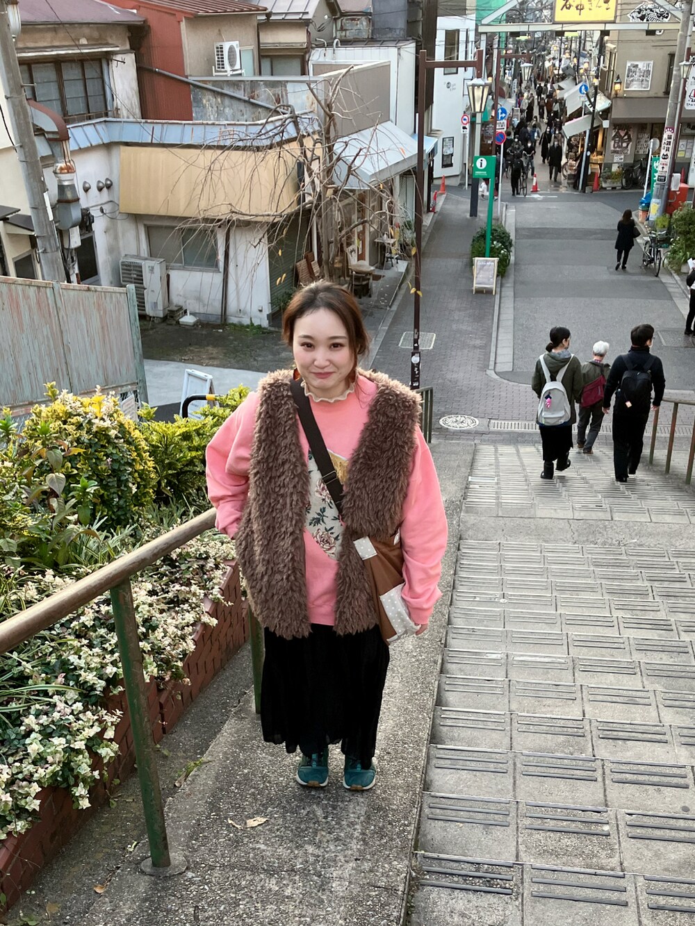 ピンク系のスウェット、ブラウン系のショルダーバッグ、ブラック系のスカートを着用したレディースの秋コーディネートの3枚目の写真