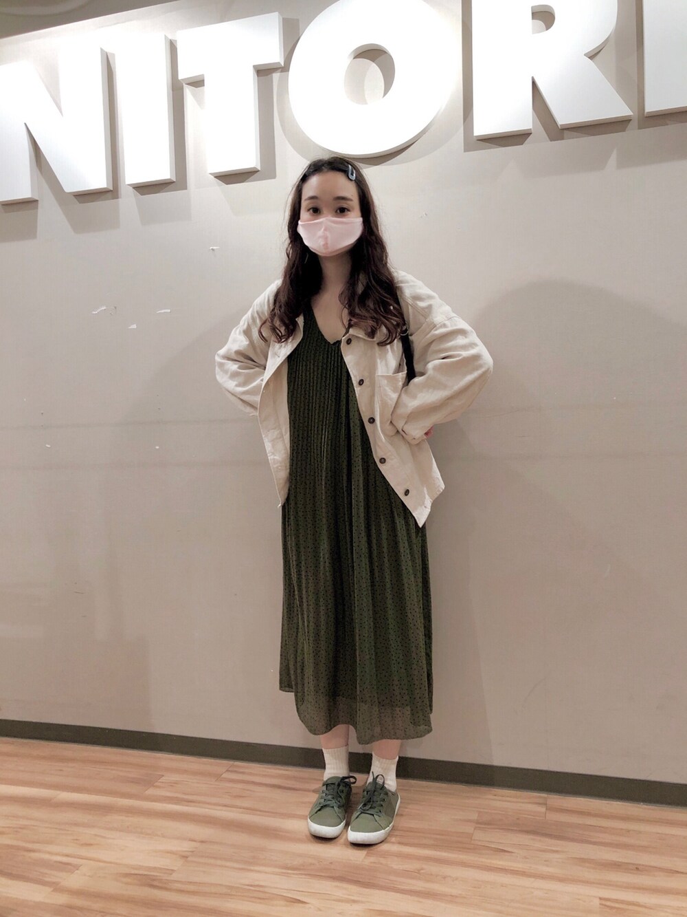 ホワイト系のミリタリージャケット、グリーン系のワンピース、ブラック系のバックパック/リュックを着用したレディースの春コーディネートの3枚目の写真