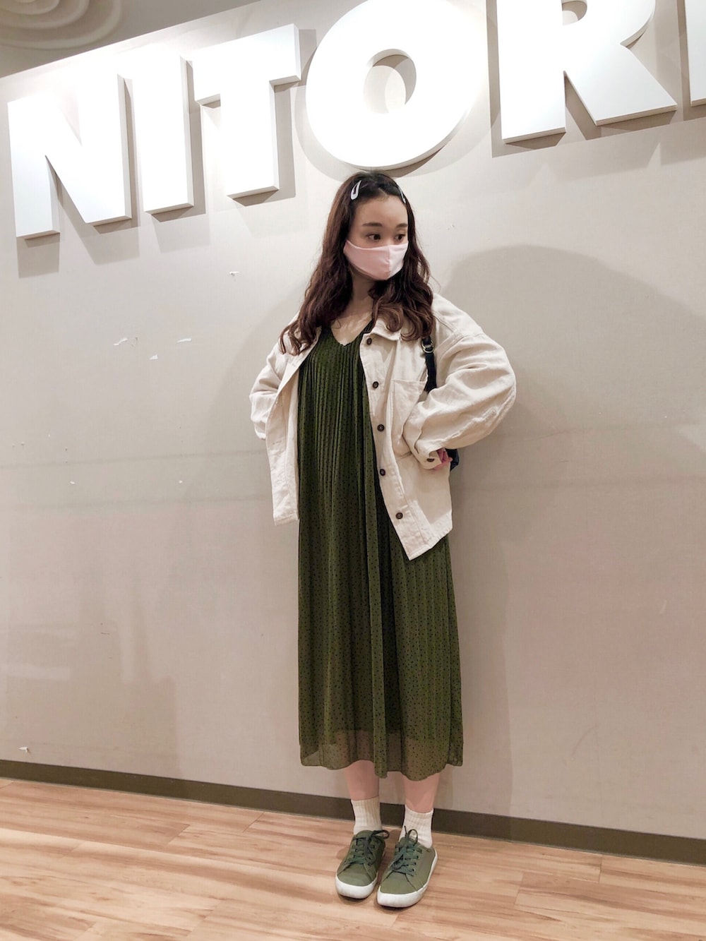 ホワイト系のミリタリージャケット、グリーン系のワンピース、ブラック系のバックパック/リュックを着用したレディースの春コーディネートの2枚目の写真