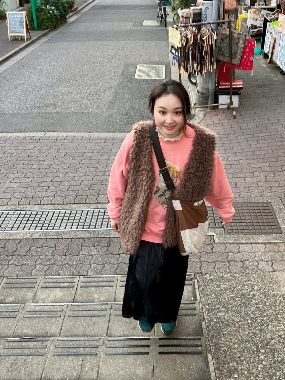 ピンク系のスウェット、ブラウン系のショルダーバッグ、ブラック系のスカートを着用したレディースの秋コーディネートの2枚目の写真