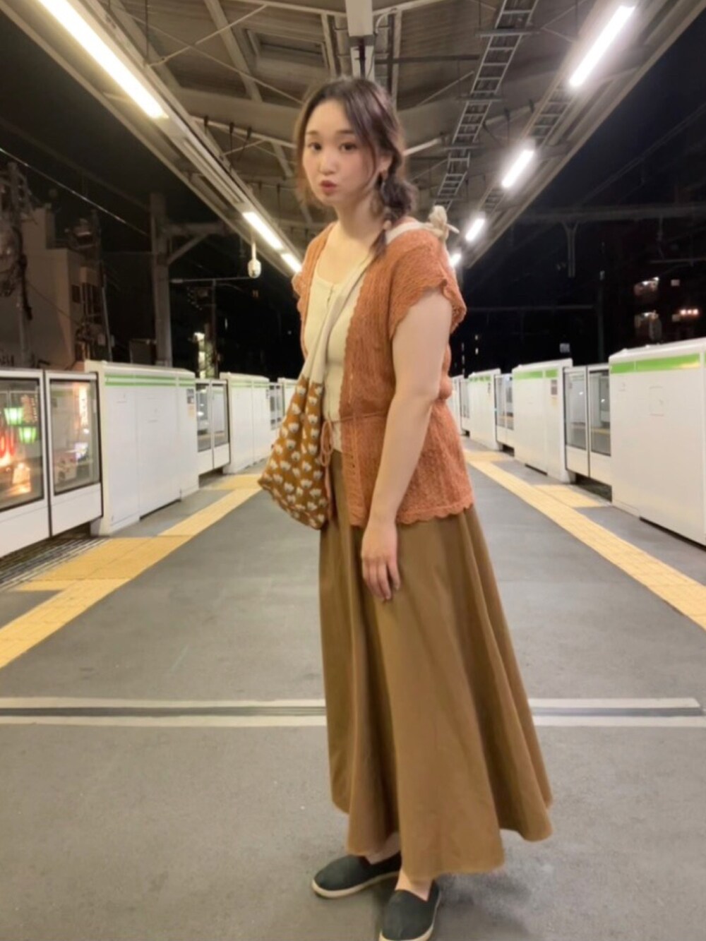 ベージュ系のタンクトップ、ブラウン系のショルダーバッグ、ブラウン系のベストを着用したレディースの秋コーディネートの3枚目の写真