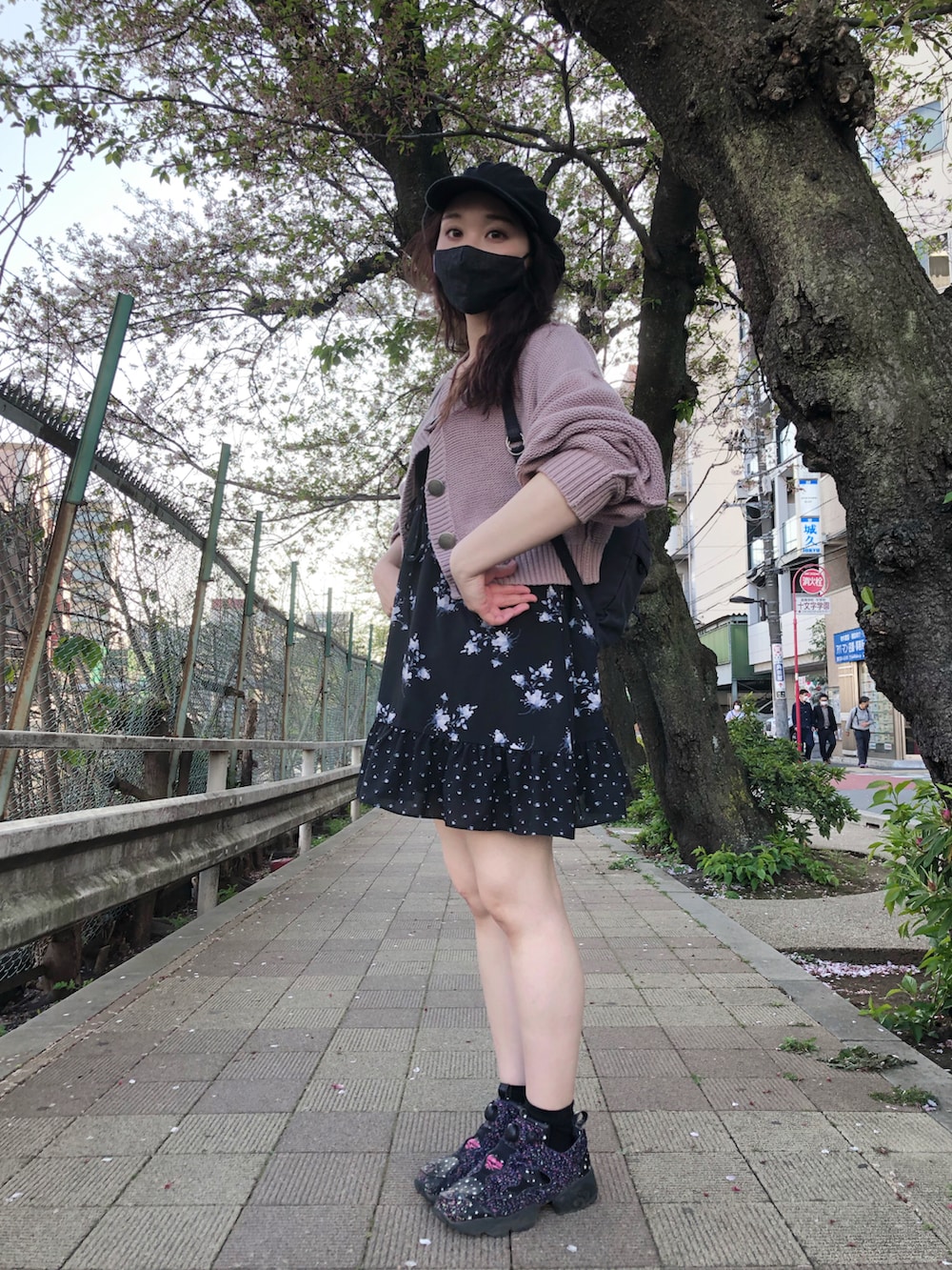 パープル系のカーディガン/ボレロ、ブラック系のワンピース、ブラック系のスニーカーを着用したレディースの春コーディネートの2枚目の写真