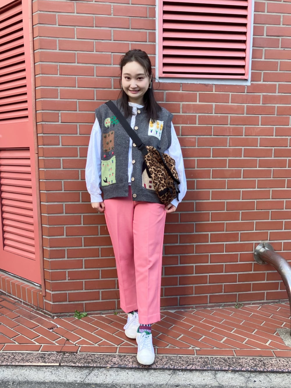 ピンク系のパンツ、ブラウン系のメッセンジャーバッグ、ホワイト系のTシャツ/カットソーを着用したレディースの秋コーディネートの2枚目の写真