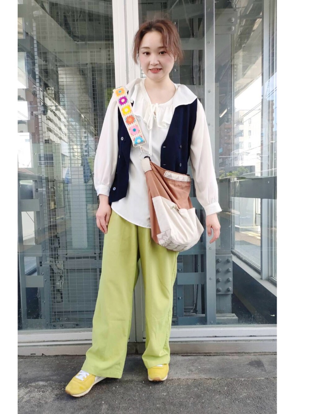 ホワイト系のシャツ/ブラウス、ブルー系のベスト、ブラウン系のショルダーバッグを着用したレディースの春コーディネートの2枚目の写真