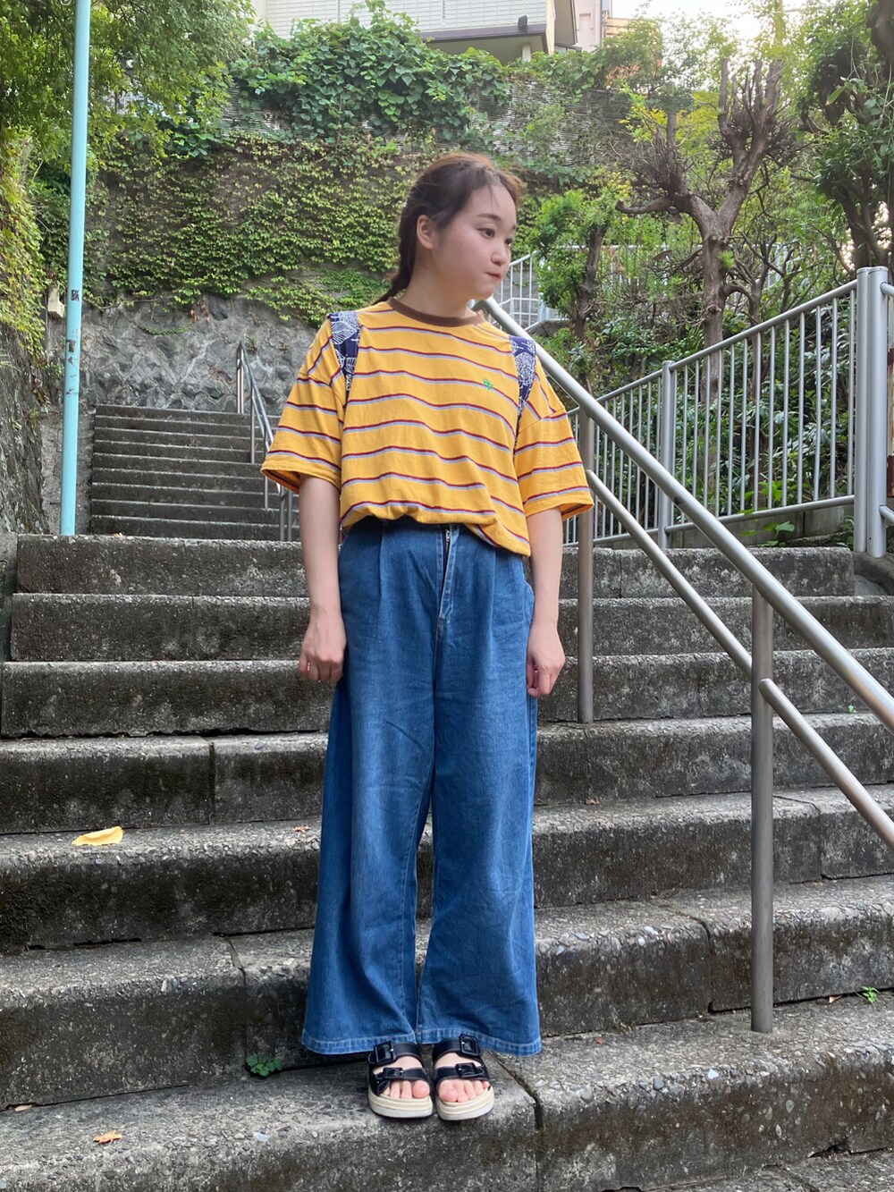 イエロー系のTシャツ/カットソー、ブルー系のデニムパンツ、ブルー系のバックパック/リュックを着用したレディースの秋コーディネートの2枚目の写真