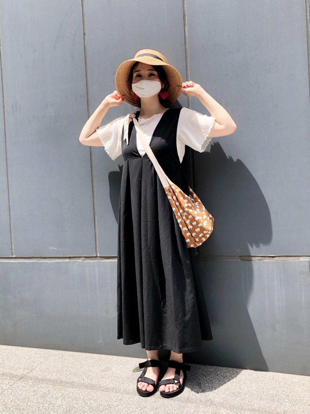 ブラウン系のショルダーバッグ、ブラック系のサンダル、ブラック系のジャンパースカートを着用したレディースの夏コーディネートの3枚目の写真