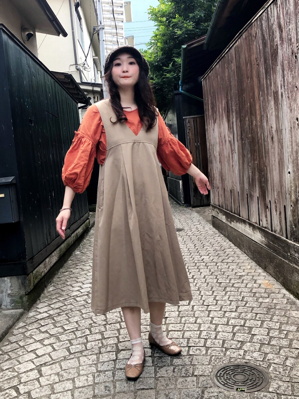 ベージュ系のジャンパースカート、ブラウン系のカーディガン/ボレロ、オレンジ系のシャツ/ブラウスを着用したレディースの秋コーディネートの2枚目の写真