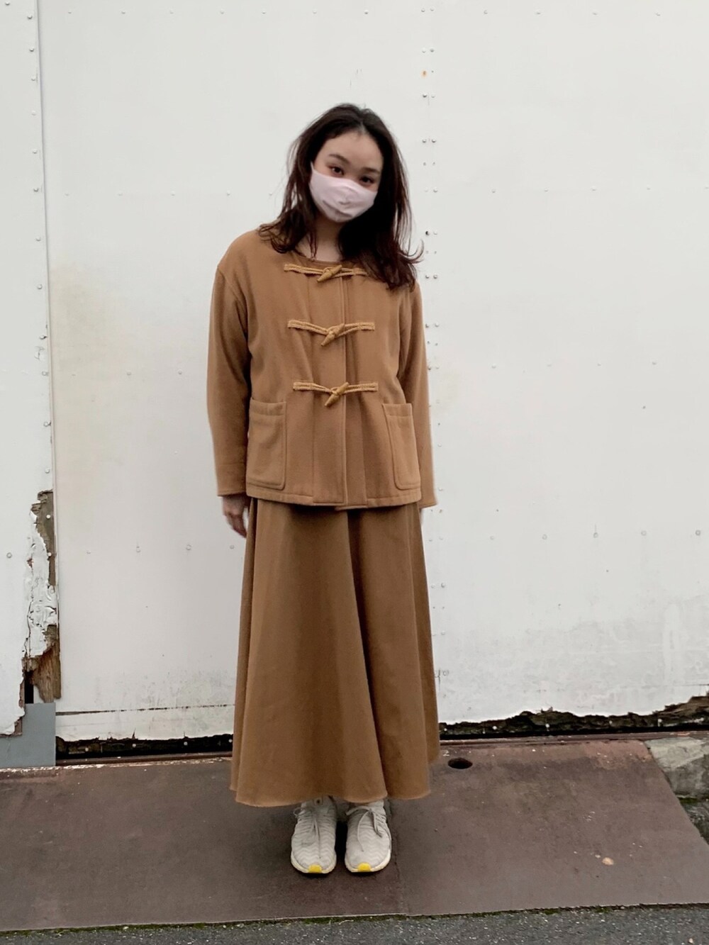 ベージュ系のダッフルコート、ブラウン系のスカート、グレー系のスニーカーを着用したレディースの秋コーディネートの3枚目の写真