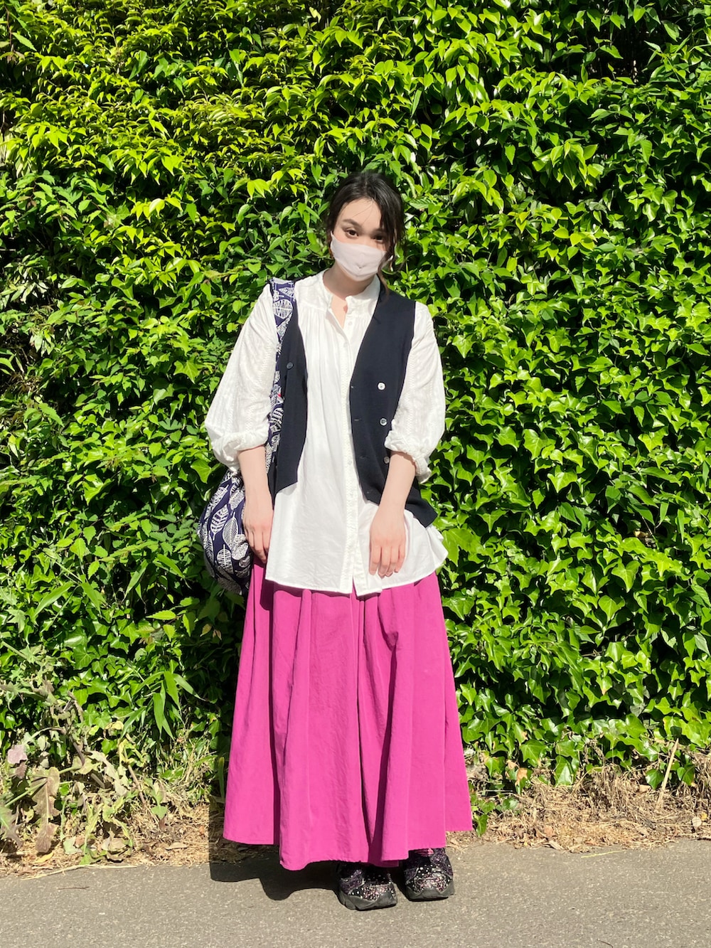 ホワイト系のシャツ/ブラウス、ブルー系のベスト、ピンク系のスカートを着用したレディースの春コーディネートの3枚目の写真