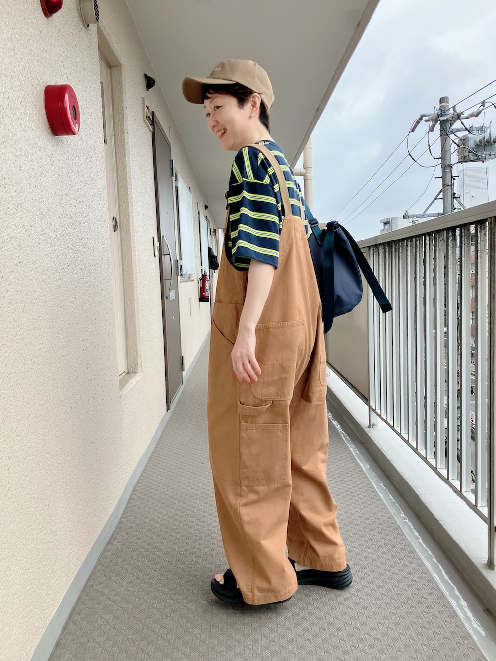 ブルー系のTシャツ/カットソー、イエロー系のサロペット/オーバーオール、ブラック系のサンダルを着用したレディースの夏コーディネートの2枚目の写真