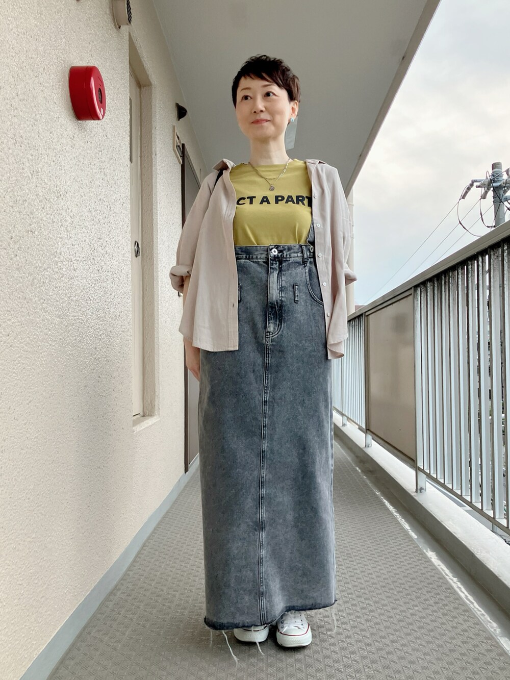 ブラック系のショルダーバッグ、イエロー系のTシャツ/カットソー、ブラック系のジャンパースカートを着用したレディースの春コーディネートの2枚目の写真