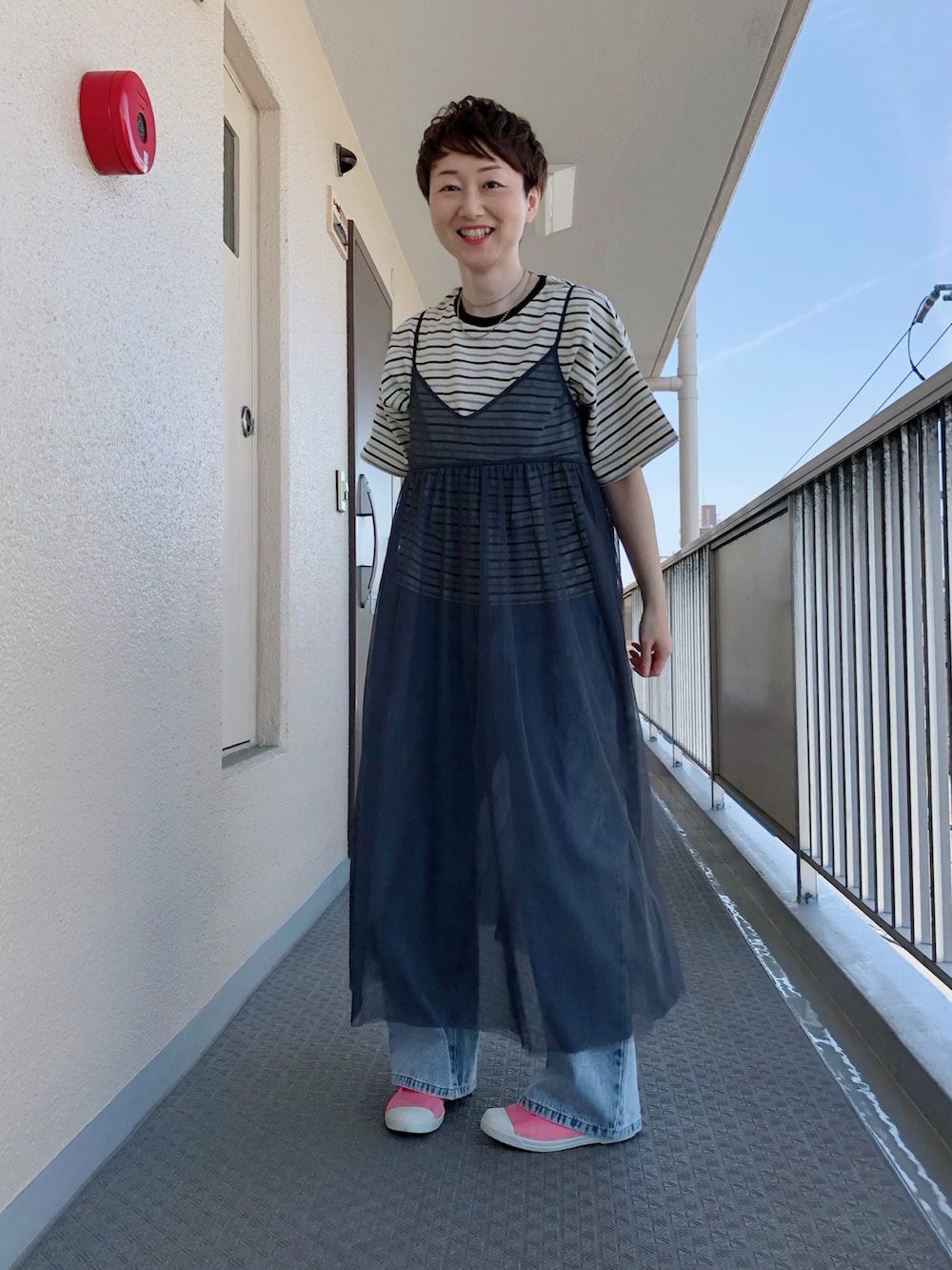 ブラック系のTシャツ/カットソー、グレー系のワンピース、ブルー系のデニムパンツを着用したレディースの春コーディネートの2枚目の写真