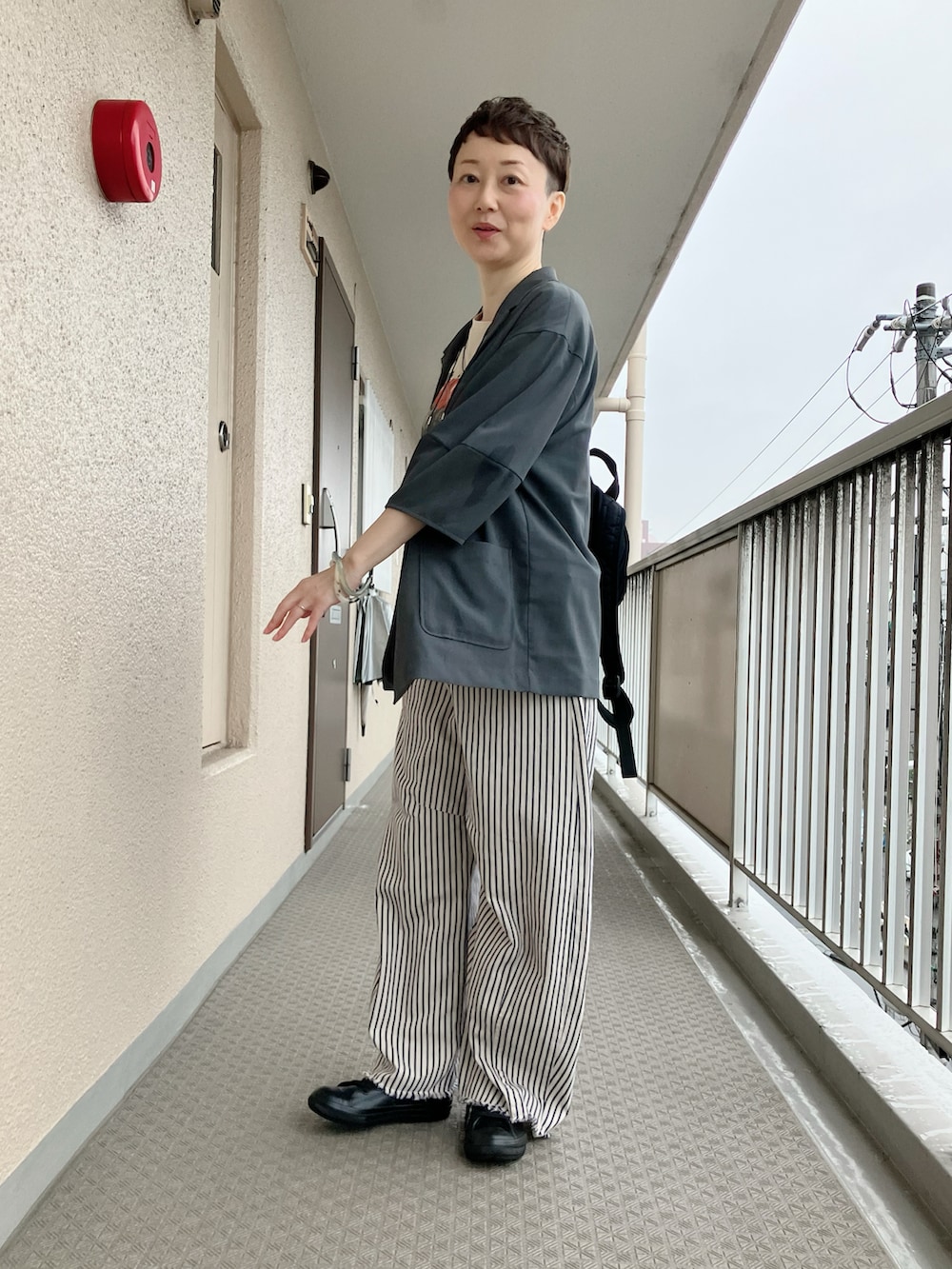ブラック系のレインシューズ、ベージュ系のTシャツ/カットソー、ホワイト系のデニムパンツを着用したレディースの秋コーディネートの2枚目の写真
