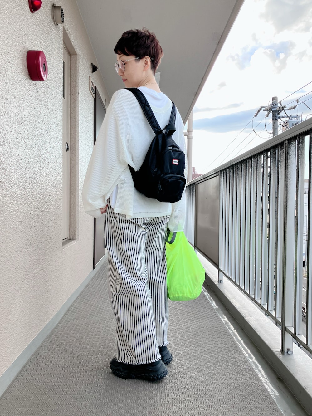 ベージュ系のニット/セーター、ホワイト系のデニムパンツ、ブラック系のバックパック/リュックを着用したレディースの春コーディネートの2枚目の写真