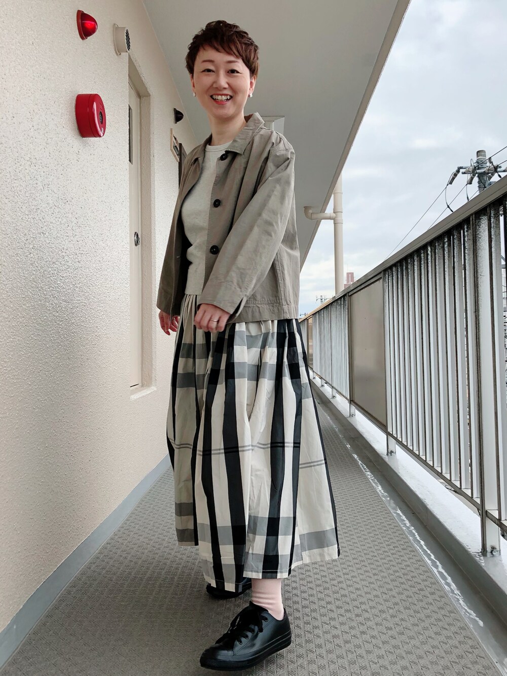 ホワイト系のスカート、ブラウン系のブルゾン、ブラック系のレインシューズを着用したレディースの秋コーディネートの2枚目の写真