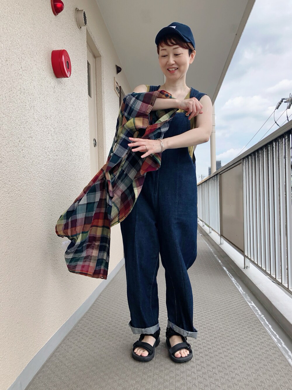 ブルー系のサロペット/オーバーオール、ブルー系のシャツ/ブラウス、ブラック系のサンダルを着用したレディースの夏コーディネートの3枚目の写真