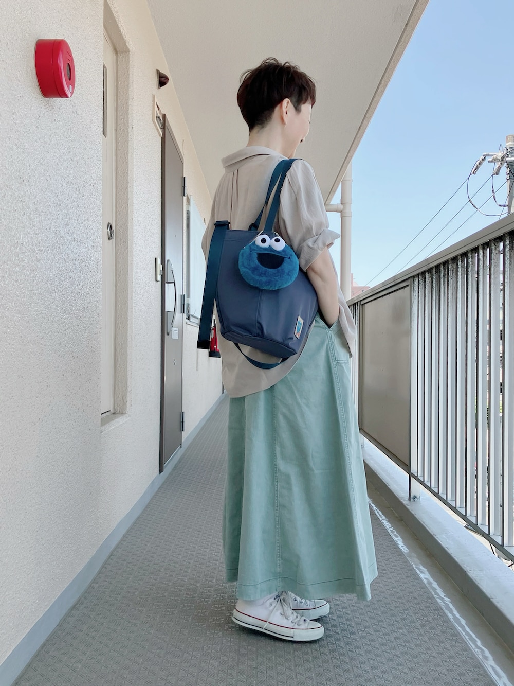 ホワイト系のTシャツ/カットソー、グリーン系のスカート、ブルー系のトートバッグを着用したレディースの春コーディネートの2枚目の写真
