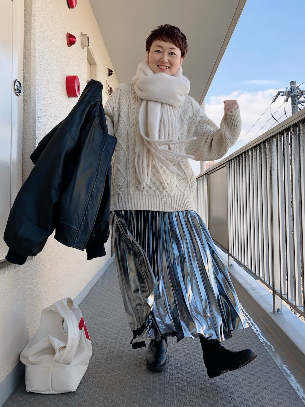 ブラック系のその他アウター、ベージュ系のニット/セーター、シルバー系のスカートを着用したレディースの冬コーディネートの4枚目の写真