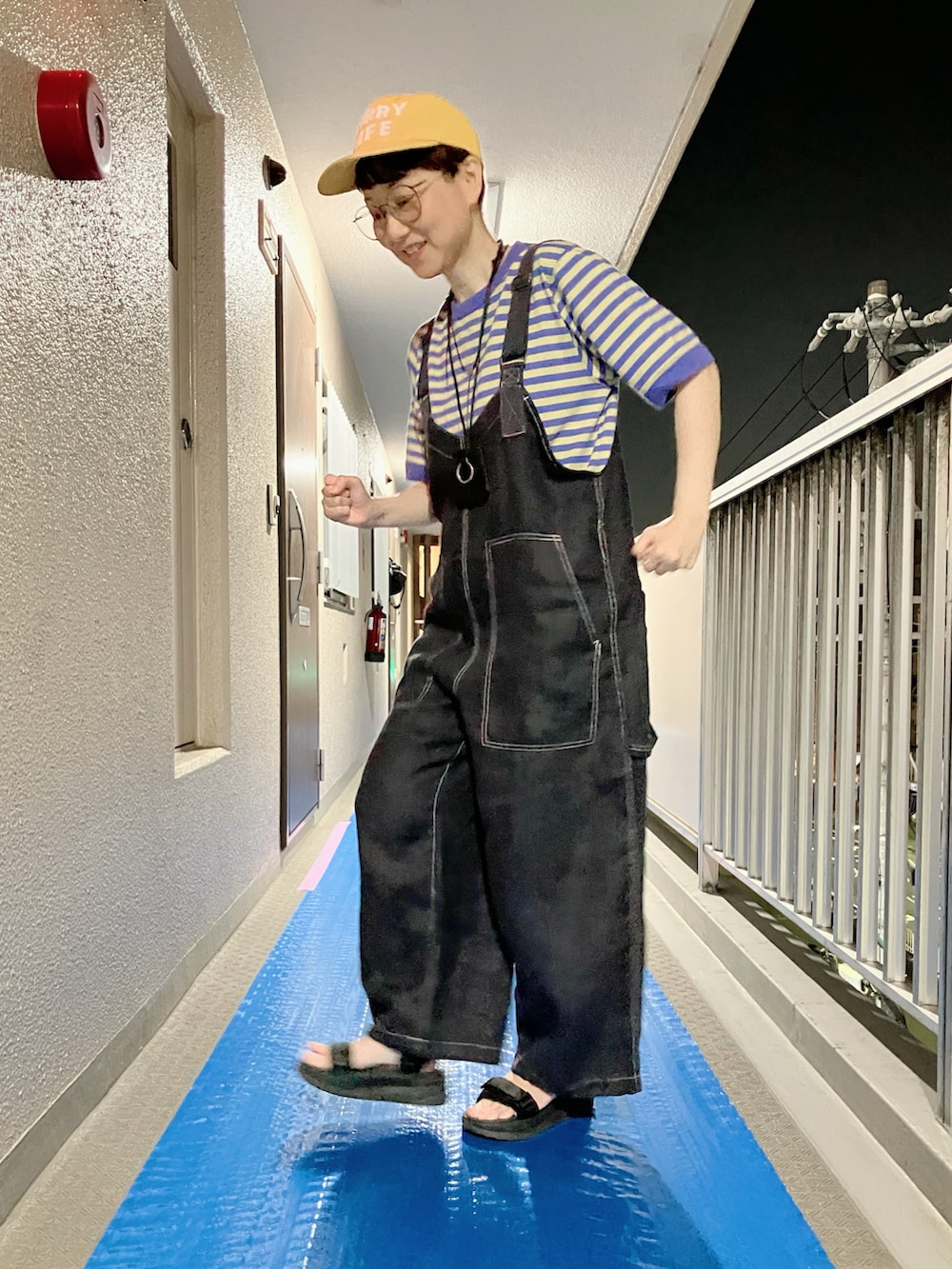 パープル系のTシャツ/カットソー、ブラック系のサロペット/オーバーオール、ブラック系のサンダルを着用したレディースの夏コーディネートの2枚目の写真
