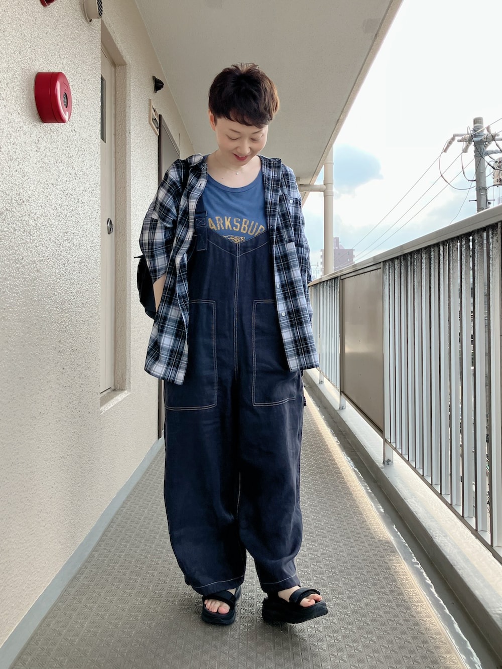 ブラック系のサロペット/オーバーオール、ブラック系のシャツ/ブラウス、ブラック系のサンダルを着用したレディースの夏コーディネートの2枚目の写真