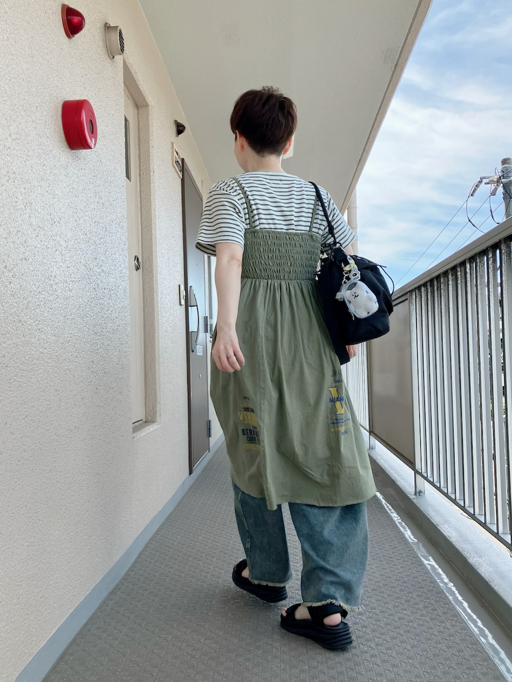 グリーン系のチュニック、ブラック系のサンダル、ブルー系のその他パンツを着用したレディースの夏コーディネートの3枚目の写真