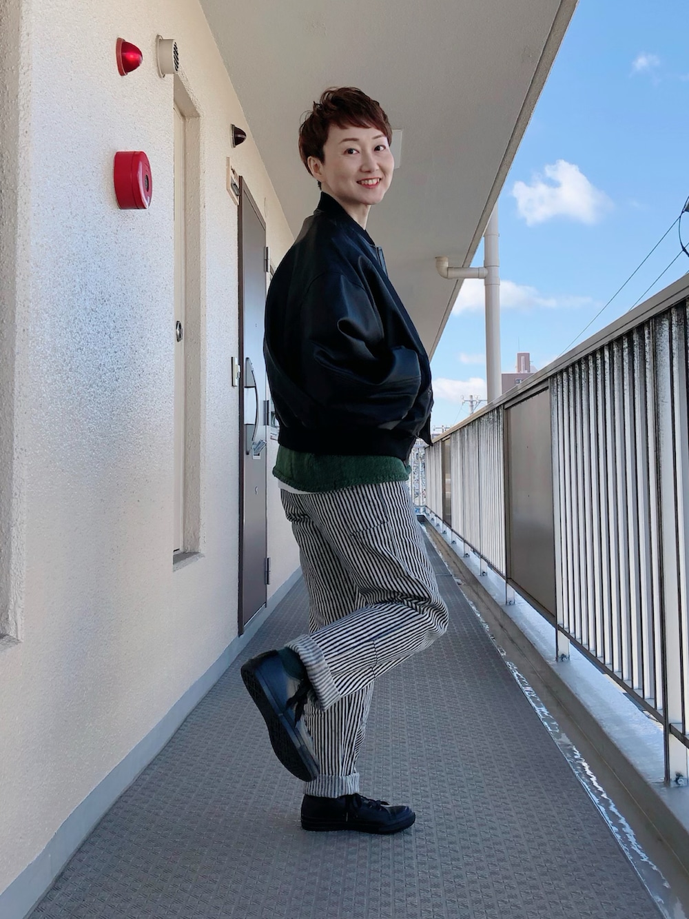 ブラック系のその他アウター、グリーン系のニット/セーター、ブルー系のデニムパンツを着用したレディースの冬コーディネートの3枚目の写真