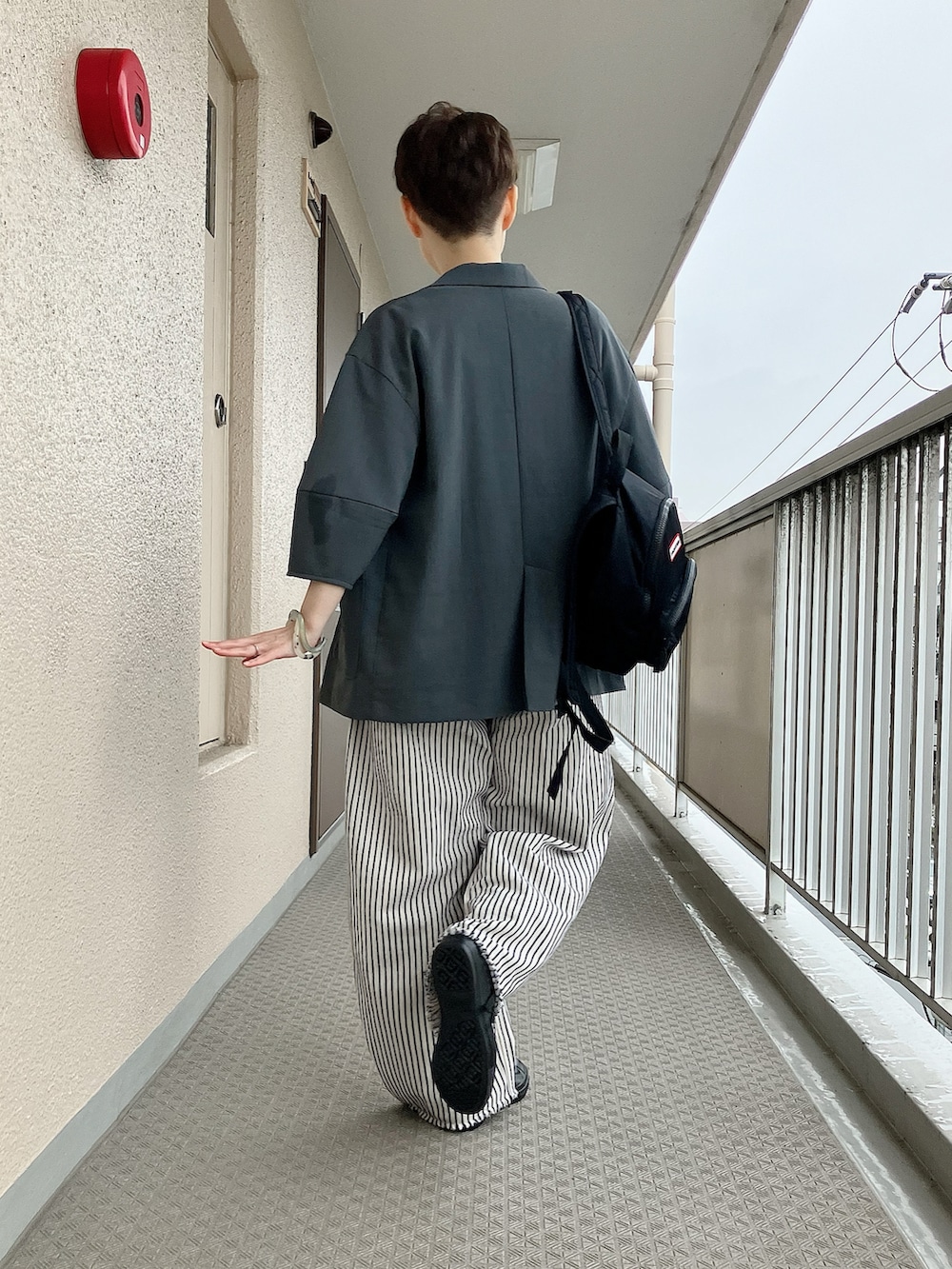 ブラック系のレインシューズ、ベージュ系のTシャツ/カットソー、ホワイト系のデニムパンツを着用したレディースの秋コーディネートの3枚目の写真