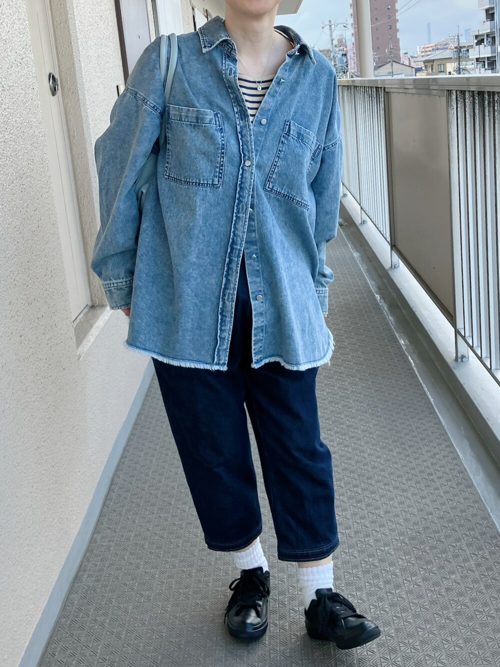 ブルー系のシャツ/ブラウス、ブルー系のサロペット/オーバーオール、ブラック系のレインシューズを着用したレディースの春コーディネートの2枚目の写真