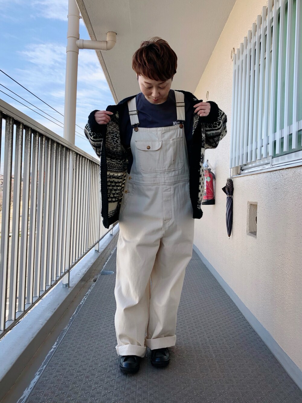 ブラック系のカーディガン/ボレロ、グレー系のTシャツ/カットソー、ホワイト系のサロペット/オーバーオールを着用したレディースの冬コーディネートの2枚目の写真