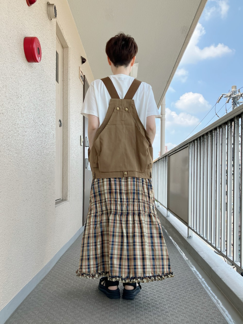 ベージュ系のベスト、ベージュ系のTシャツ/カットソー、イエロー系のスカートを着用したレディースの夏コーディネートの3枚目の写真