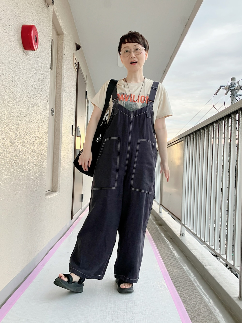 ベージュ系のTシャツ/カットソー、ブラック系のサロペット/オーバーオール、ブラック系のトートバッグを着用したレディースの夏コーディネートの2枚目の写真