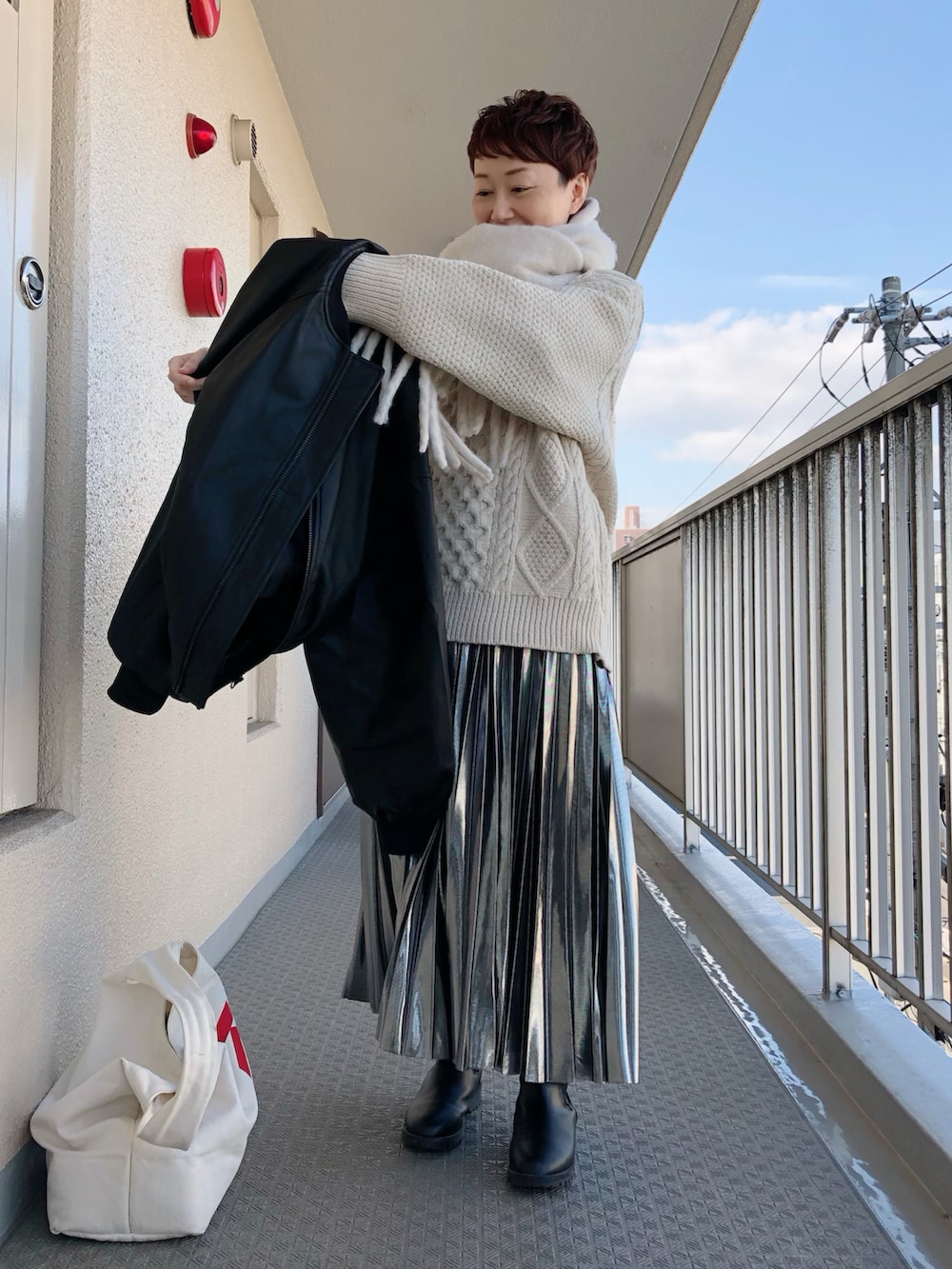 ブラック系のその他アウター、ベージュ系のニット/セーター、シルバー系のスカートを着用したレディースの冬コーディネートの3枚目の写真