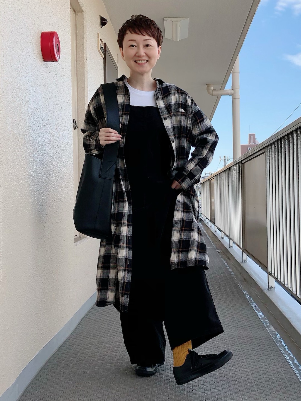 ブラック系のショルダーバッグ、ブラック系のワンピース、ホワイト系のサロペット/オーバーオールを着用したレディースの秋コーディネートの2枚目の写真