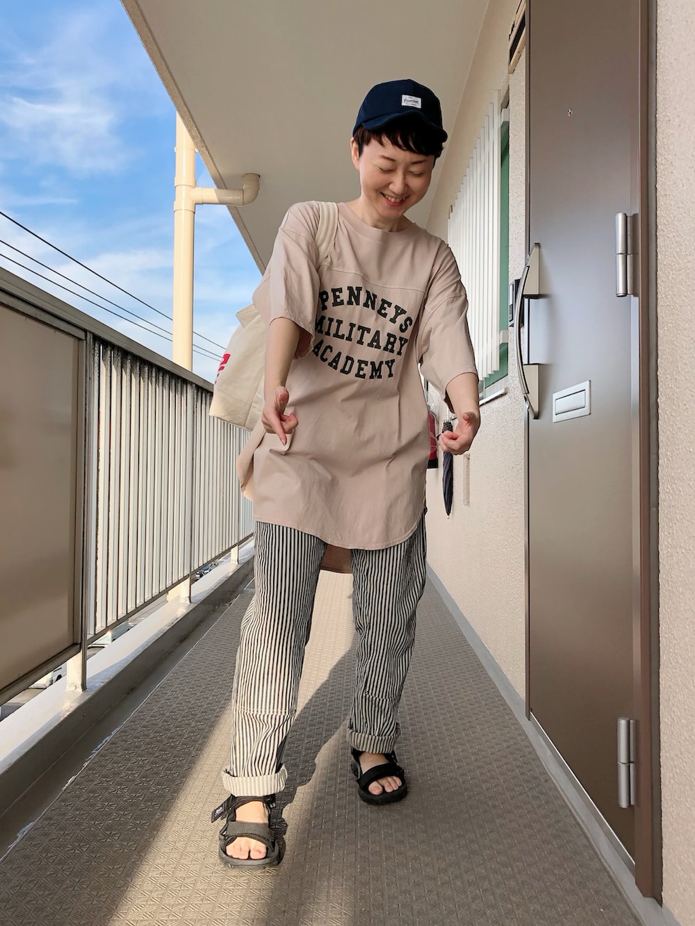 ベージュ系のTシャツ/カットソー、ホワイト系のショルダーバッグ、ブラック系のサンダルを着用したレディースの夏コーディネートの2枚目の写真