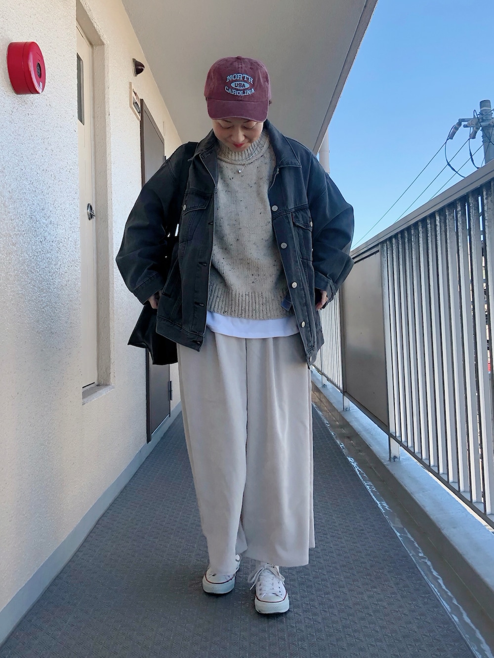 ブラック系のデニムジャケット、ベージュ系のニット/セーター、ホワイト系のパンツを着用したレディースの冬コーディネートの2枚目の写真