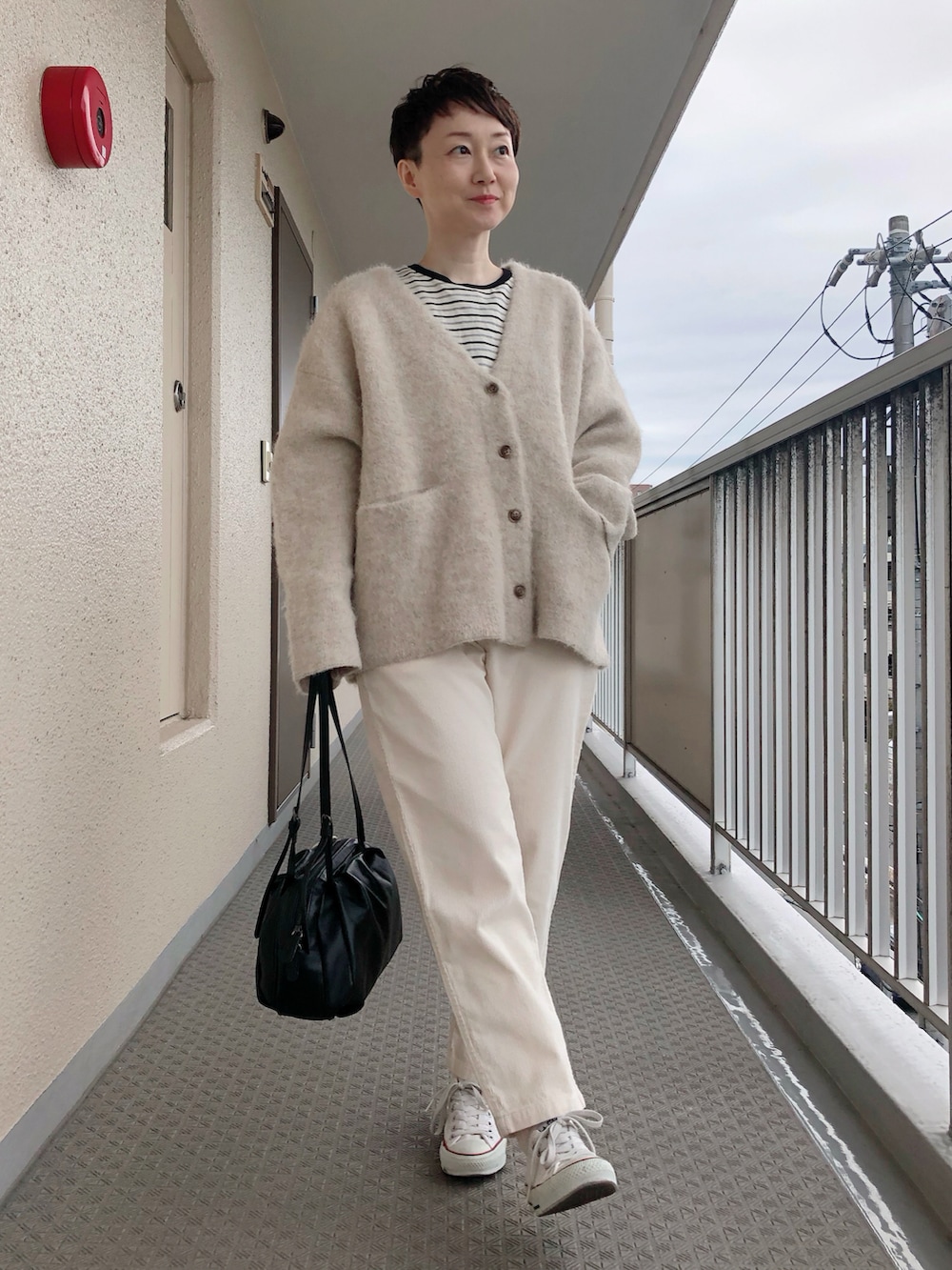 ベージュ系のカーディガン/ボレロ、ブラック系のTシャツ/カットソー、ブラック系のボストンバッグを着用したレディースの秋コーディネートの2枚目の写真