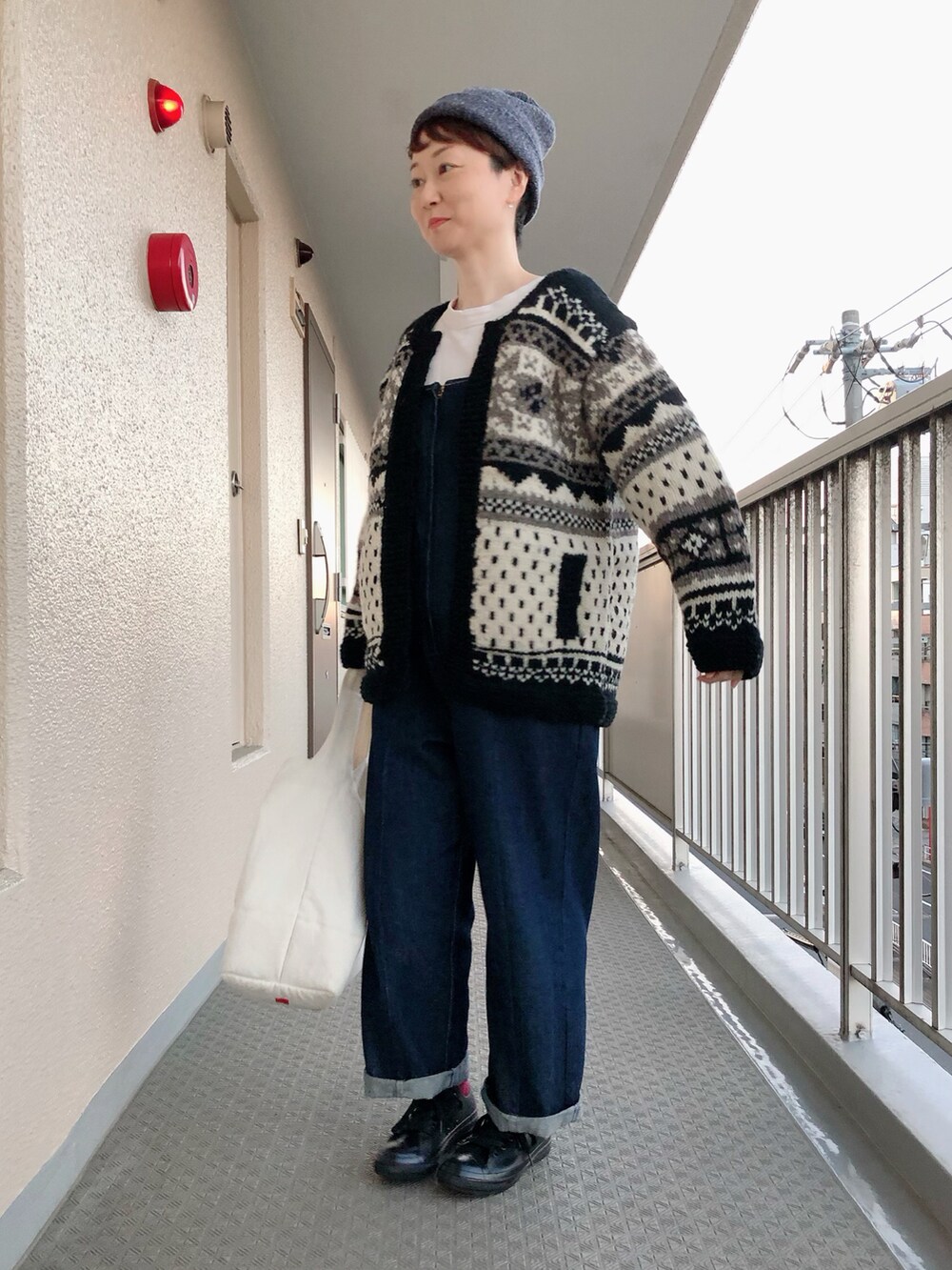 ブラック系のカーディガン/ボレロ、ブルー系のサロペット/オーバーオール、イエロー系のショルダーバッグを着用したレディースの秋コーディネートの2枚目の写真