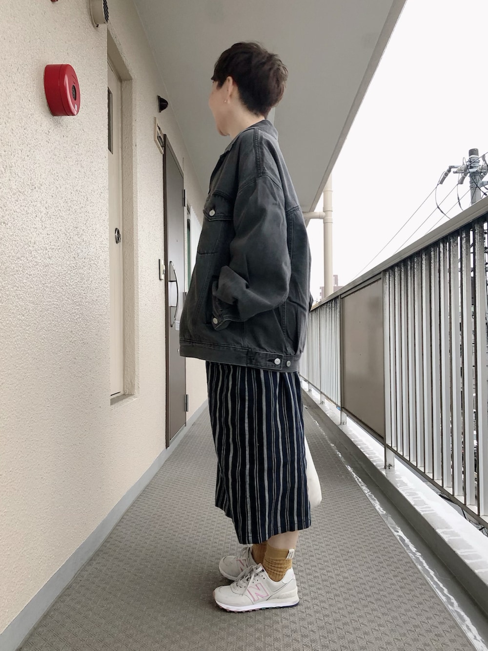 ブラック系のデニムジャケット、ベージュ系のスウェット、ブルー系のワンピースを着用したレディースの春コーディネートの2枚目の写真