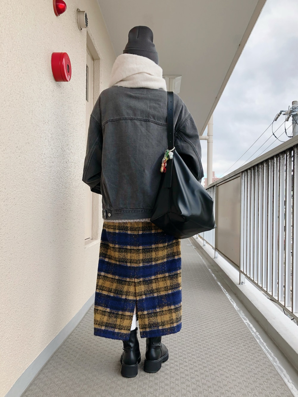 ブラック系のデニムジャケット、ベージュ系のニット/セーター、ブルー系のスカートを着用したレディースの冬コーディネートの2枚目の写真