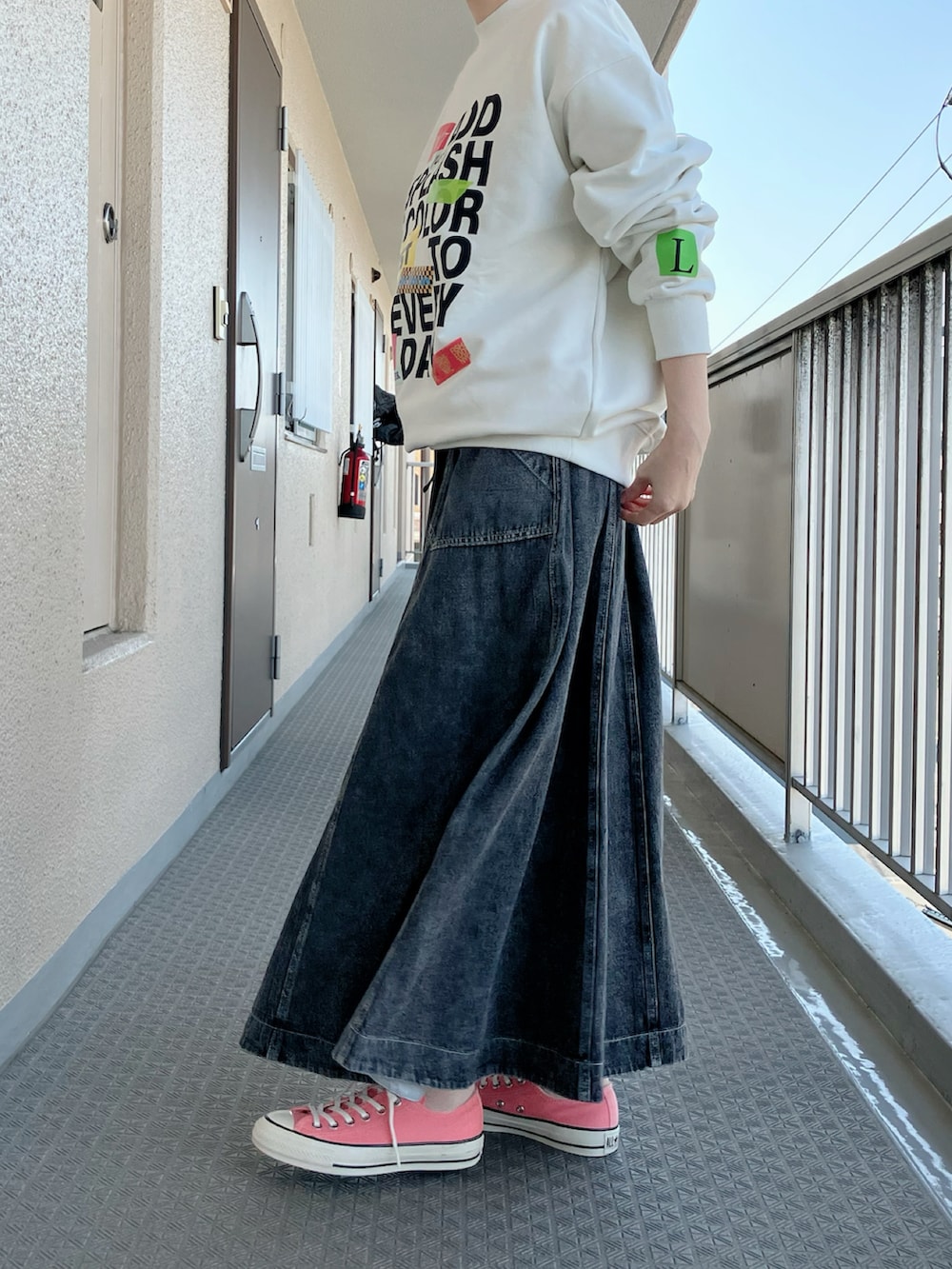 ホワイト系のスウェット、ブラック系のデニムスカート、ピンク系のスニーカーを着用したレディースの春コーディネートの2枚目の写真
