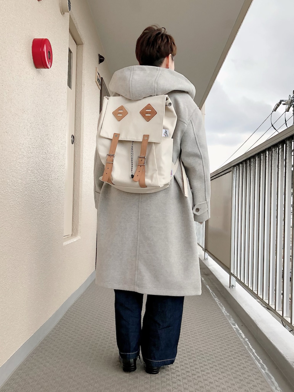 グレー系のダッフルコート、ブルー系のサロペット/オーバーオール、レッド系のニット/セーターを着用したレディースの冬コーディネートの3枚目の写真