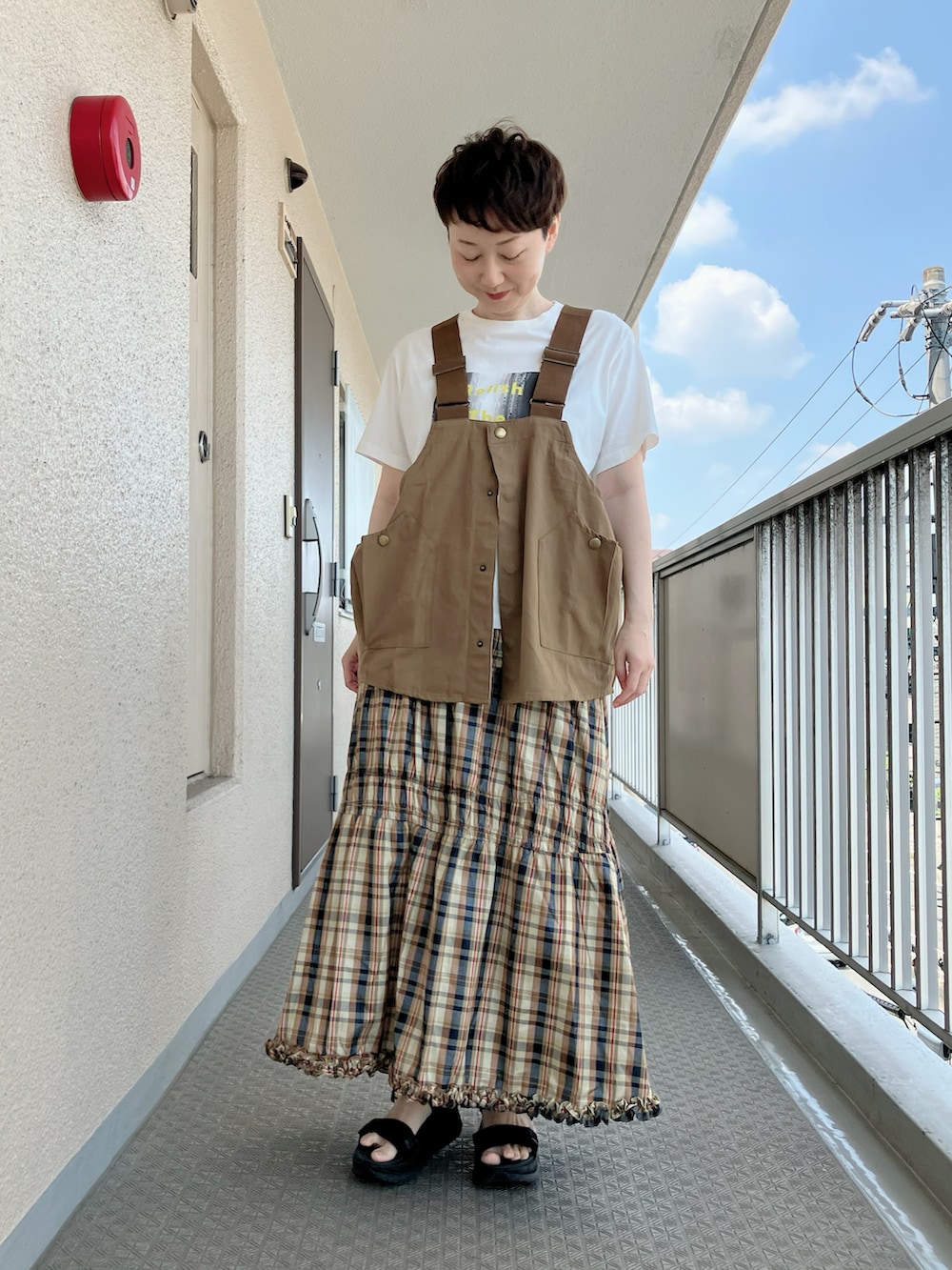 ベージュ系のベスト、ベージュ系のTシャツ/カットソー、イエロー系のスカートを着用したレディースの夏コーディネートの2枚目の写真