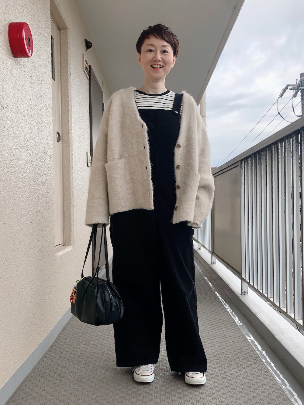ベージュ系のカーディガン/ボレロ、ブラック系のTシャツ/カットソー、ブラック系のボストンバッグを着用したレディースの秋コーディネートの2枚目の写真