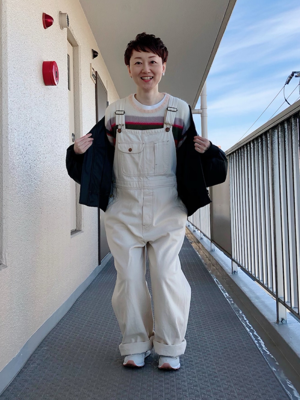 ブラック系のその他アウター、ホワイト系のサロペット/オーバーオール、ホワイト系のスニーカーを着用したレディースの冬コーディネートの2枚目の写真