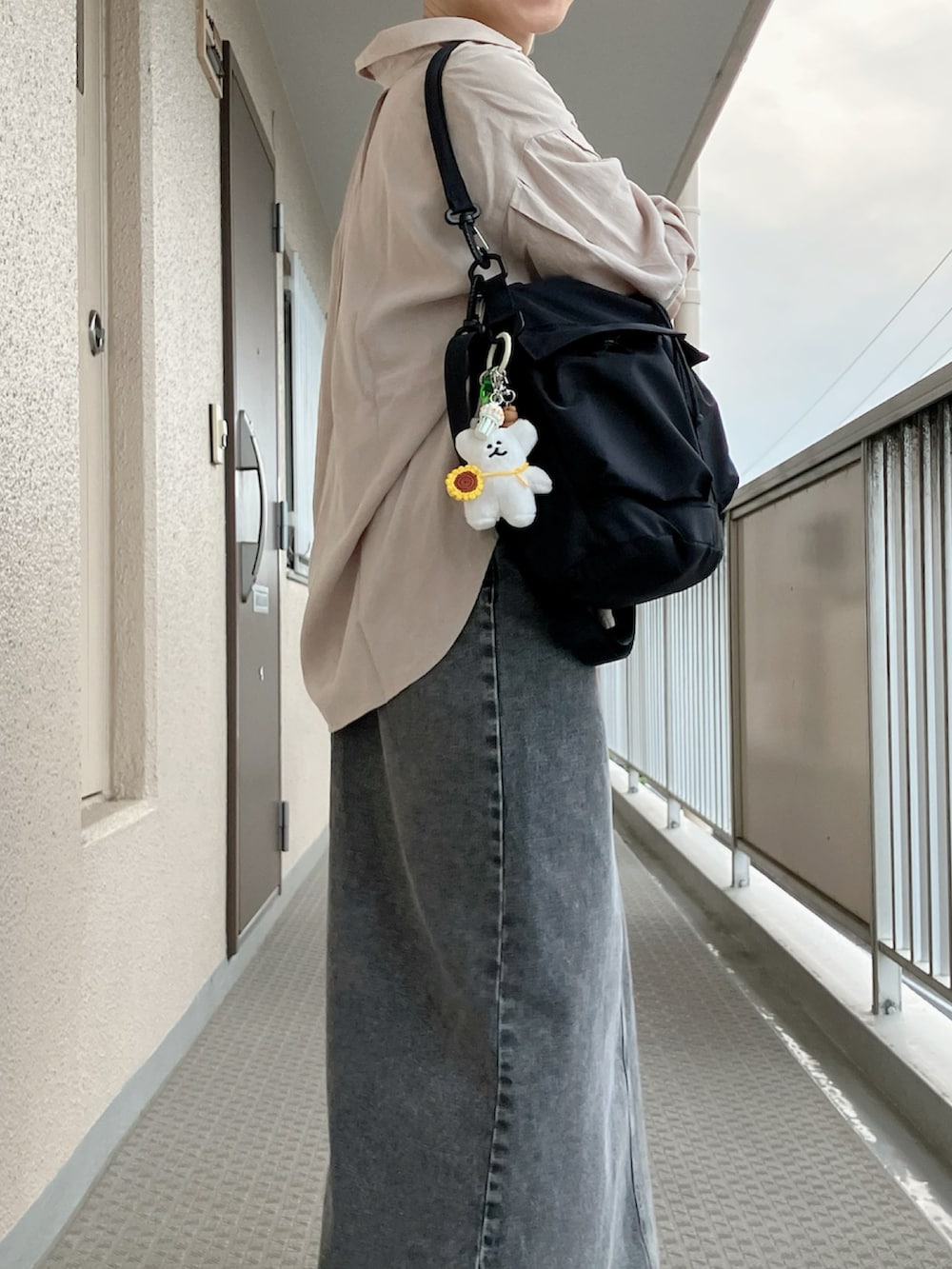 ブラック系のショルダーバッグ、イエロー系のTシャツ/カットソー、ブラック系のジャンパースカートを着用したレディースの春コーディネートの3枚目の写真