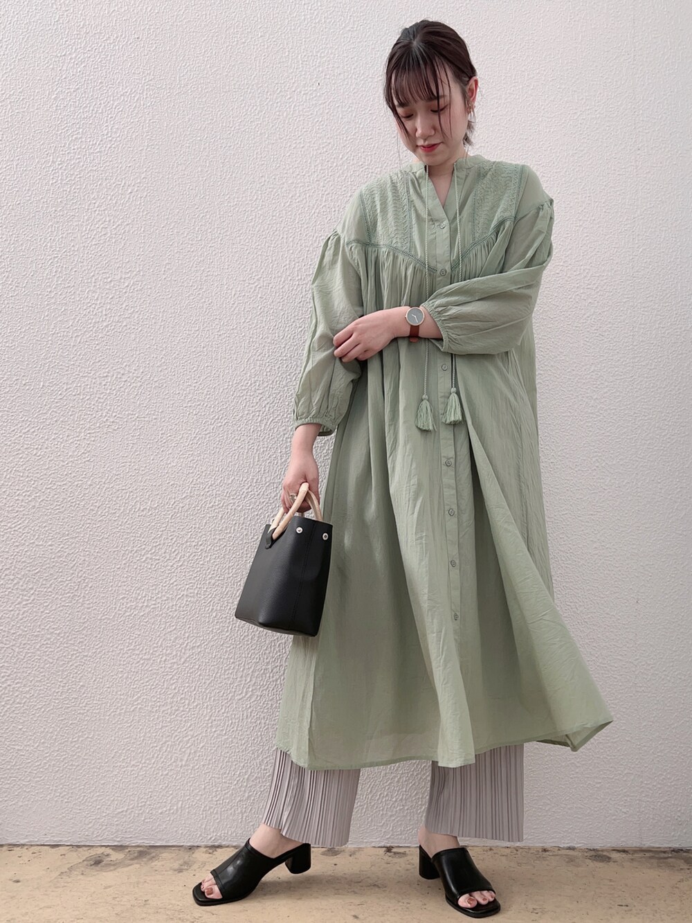 グリーン系のワンピース、ブラック系のトートバッグ、ブラック系のシューズを着用したレディースの春コーディネートの2枚目の写真